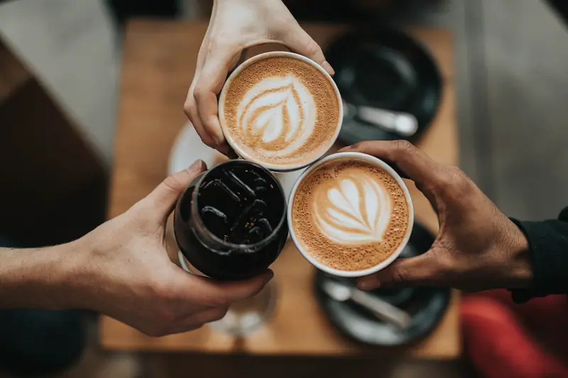 Three hands raising coffee cups together